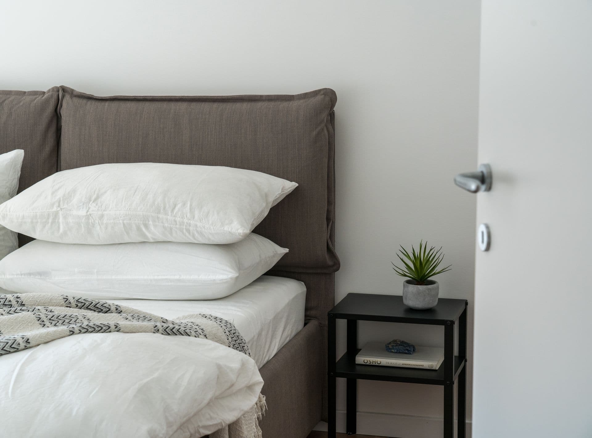 Freshly made bed with crisp white linens in a bright, professionally cleaned bedroom